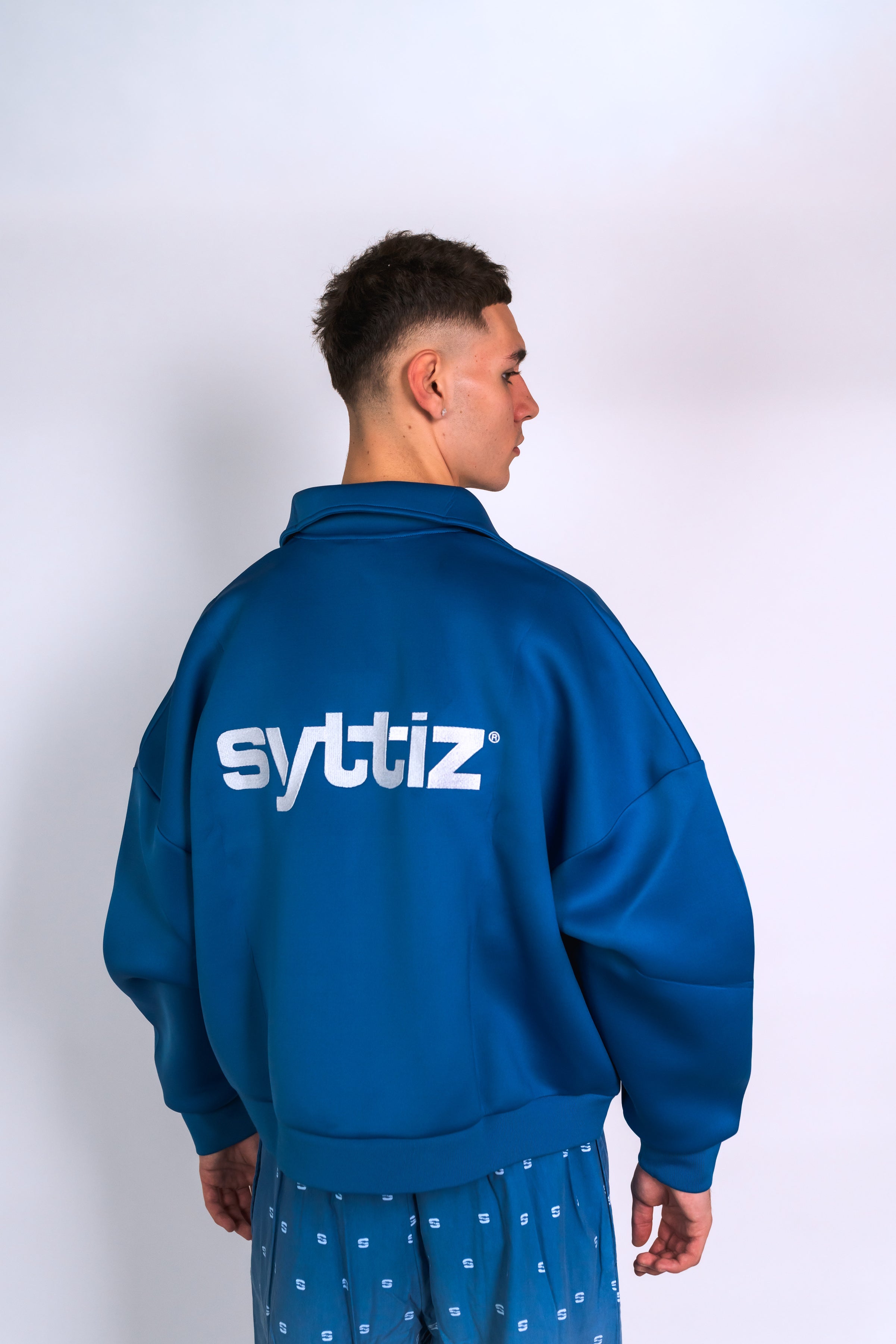 Découvre l’ensemble streetwear bleu Syttiz : sweat à col zippé et pantalon dégradé bleu/blanc. Style urbain, coupe oversize et confort premium signé Syttiz.